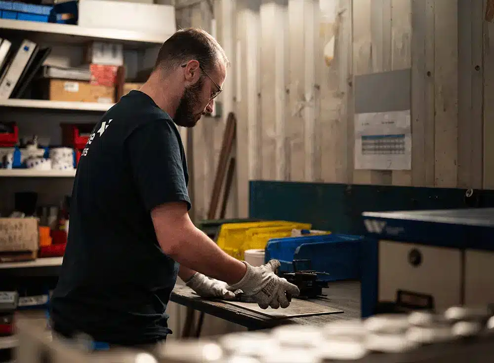 Un homme qui réalise un poinçonnage industriel chez Claude Industries