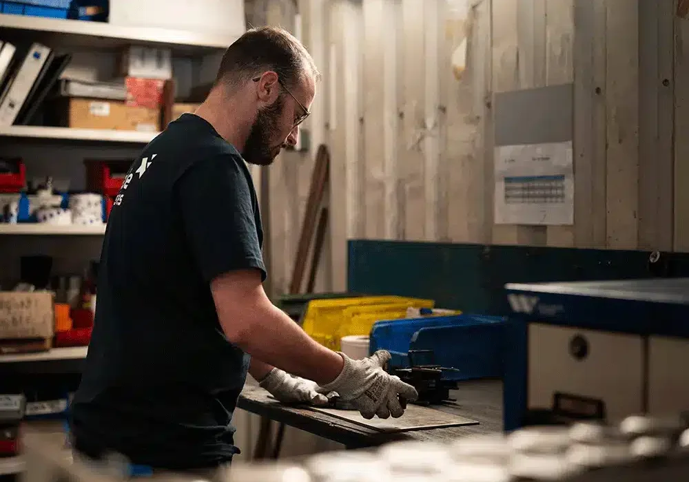 Un homme qui réalise un poinçonnage industriel chez Claude Industries